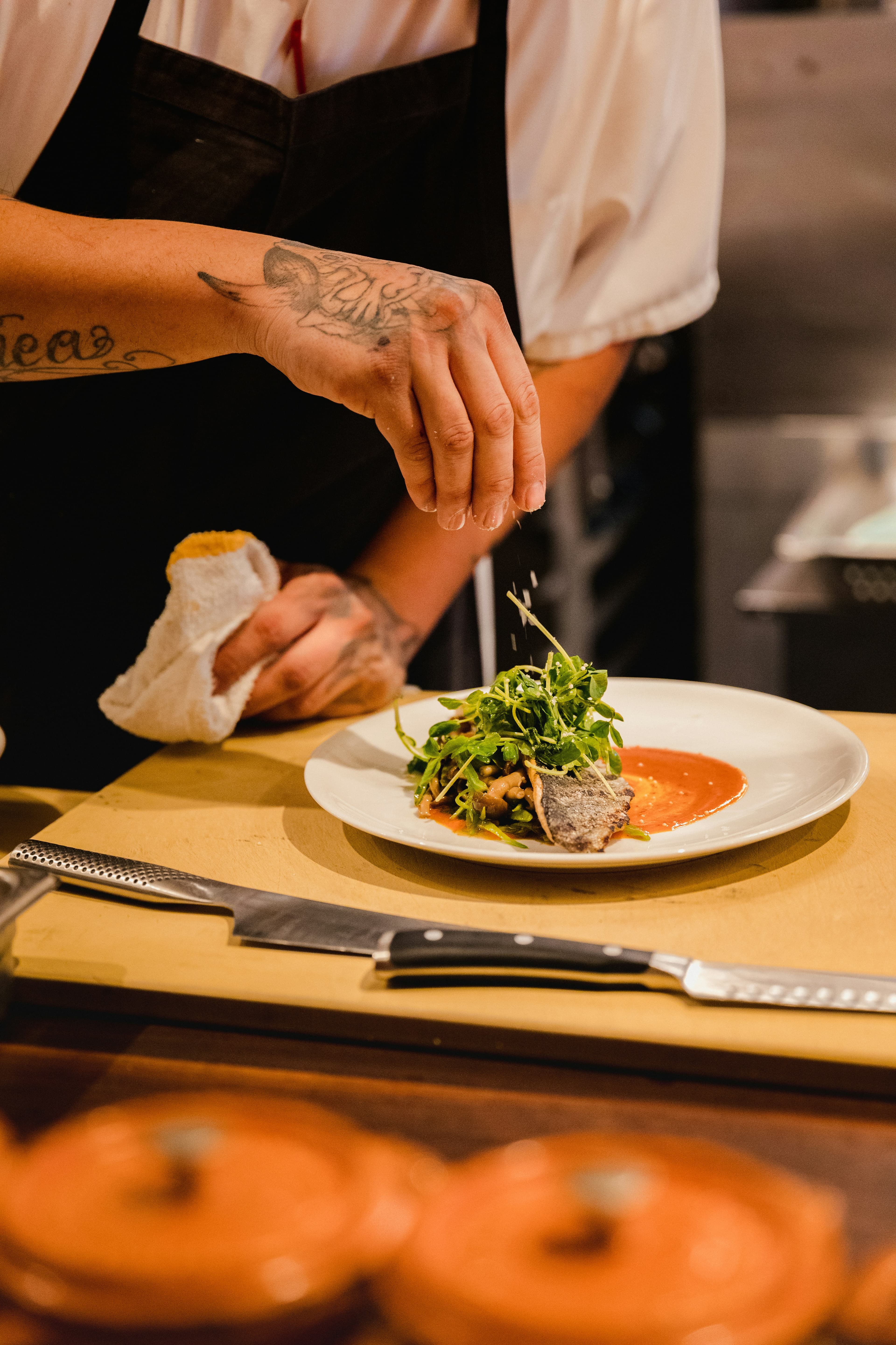 Cuisinier en intérim — Cuisinier en toque préparant un plat dans une cuisine professionnelle